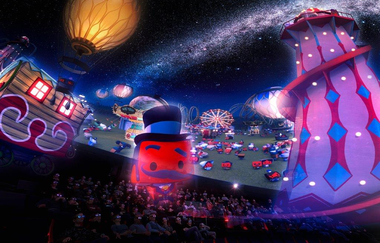 Das Bild zeigt eine Menschenmenge auf Sitzen, die an eine kugelförmige Decke schauen. Die Decke besteht aus einer Leinwand, die einen Animationsfilm mit einer roten Figur, einem Turm und einem gelben Heißluftballon zeigt. Der Raum ist dunkel.
