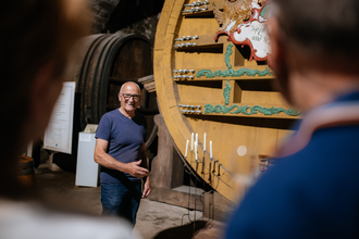 Museumsführer steht vor dem Weinfass. | © Hohenloher Perlen