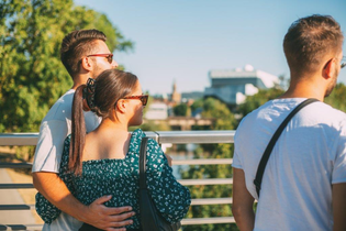 drei Personen stehen vor einem Geländer und schauen in die Ferne . Im Hintergrund ist verschwommen ein weißes Gebäude erkennbar