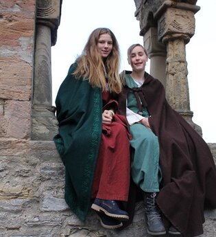 Kinderstadtführerinnen in historischer Aufmachung sitzen an den Arkaden des ehemaligen staufischen Palas | © Stadt Bad Wimpfen