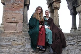 Kinderstadtführerinnen in historischer Aufmachung sitzen an den Arkaden des ehemaligen staufischen Palas | © Stadt Bad Wimpfen