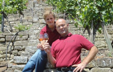 Famile Schaaf an den Weinreben mit jeweils einem Glas Wein in der Hand