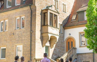 Gruppe steht vor einem spätmittelalterlichem Natursteinhaus im Heilbronner Deutschhof