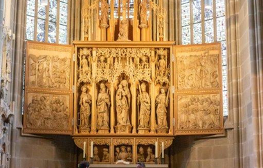 Gruppe steht vor dem imposanten, aus Holz geschnitzten Seyffer-Altar. Der Stadtführer in der Gruppe versorgt die Gruppe mit Informationen