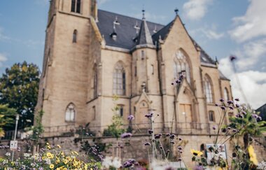 Die evangelische Stadtkirche mit Blumenbeet im Vordergrund. | © Stadt Bad Rappenau I Chris Frumolt
