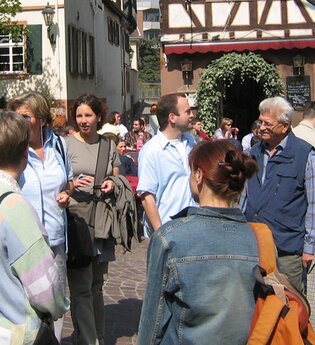 Personen stehen während einer Führung auf dem Marktplatz im Hintergrund Fachwerkgebäude | © Maria Zimmermann