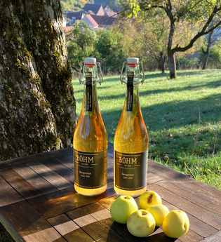 Cider und Streuobst-Äpfel auf einer Holzablage mitten in der Streuobstwiese | © Touristikgemeinschaft Hohenlohe | Manfred Böhm