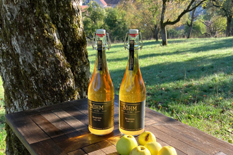 Cider und Streuobst-Äpfel auf einer Holzablage mitten in der Streuobstwiese | © Touristikgemeinschaft Hohenlohe | Manfred Böhm