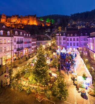 Winterwäldchen auf dem Kornmarkt mit weihnachtlichen Tannen und dem Heidelberger Schloss im Hintergrund. | © Heidelberg Marketing GmbH / Jan Becke