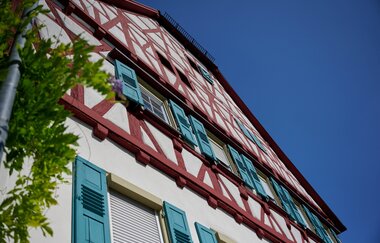 Ein prächtiges Fachwerkhaus mit roten Balken und türkisfarbenen Fensterläden vor strahlend blauem Himmel. | © Kraichgau-Stromberg Tourismus e.V.