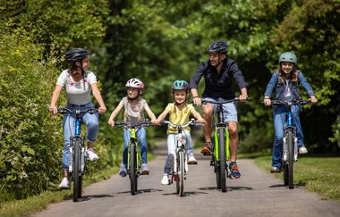 Familie mit drei Kindern fahren im Grünen | © @Spessart Mainland/TOURISMUS REGION WERTHEIM/Holger Leue