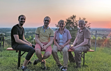 4 Personen sitzen auf einer Bank in einem Weinberg bei Sonnenuntergang | © Dieter König