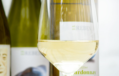 Ein Glas Weißwein vor mehreren Flaschen | © Dieter König