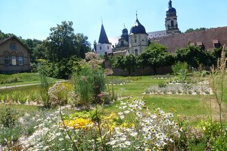 Im Garten blühen Arzneipflanzen und man kann auf das Kloster schauen | © Touristikgemeinschaft Hohenlohe e. V. | Hohenloher Gartenparadies