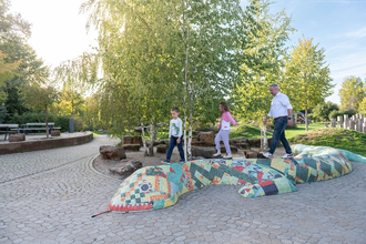 Kinder laufen über eine bunte Steinschlange im alla hopp!-Park