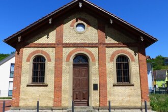 Synagoge aus Backsteinen mit großer Holztüre und zwei Fenstern vor blauem Himmel | © Alte Synagoge Steinsfurt