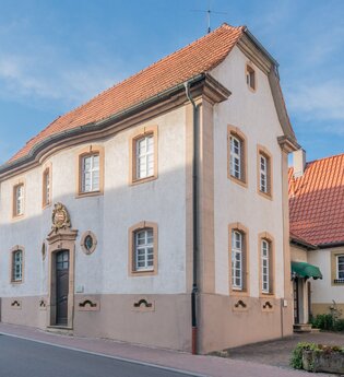 Renoviertes historisches Gebäude mit rotem Ziegeldach an einer Straße