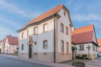 Renoviertes historisches Gebäude mit rotem Ziegeldach an einer Straße