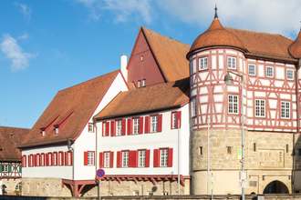 altes Schloss - rechts das Torhaus mit Sockelgeschoss aus hellem Sandstein und aufgesetztem roten Fachwerk mit weißen Gefachen, flankiert von zwei Rundtürmen. In der Bildmitte der Westflügel mit zwei aneinandergebauten, weiß verputzten Gebäudeteilen mit r | © Stadt Gaildorf