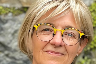 lächenlnde Frau mit blonden Haaren und Brille vor einen begrünten Mauer | © Anja Schué