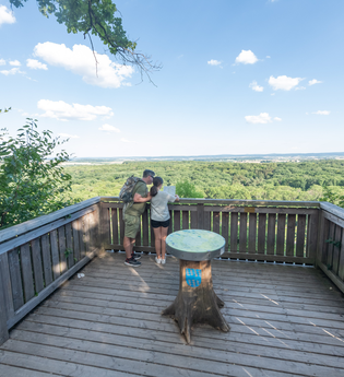 Hölzerne Plattform mit zwei Personen und Blick auf den Wald