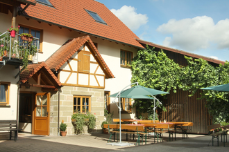 Die Weinstube hat außen eine Sommerterrasse mit Biertischen und Sonnenschirmen | © Touristikgemeinschaft Hohenlohe e. V. | Baldeles Weinstube