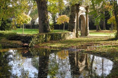 Alter Steinbogen im Park an einem Teich im Herbst