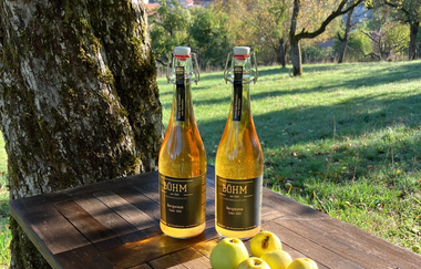 Cider und Streuobst-Äpfel auf einer Holzablage mitten in der Streuobstwiese | © Touristikgemeinschaft Hohenlohe | Manfred Böhm