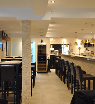 Der helle Innenräume verfügt über schwarze Barhocker an der Wand und um den Tresen | © Touristikgemeinschaft Hohenlohe e. V. | Café de Paris