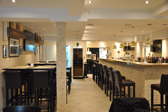 Der helle Innenräume verfügt über schwarze Barhocker an der Wand und um den Tresen | © Touristikgemeinschaft Hohenlohe e. V. | Café de Paris