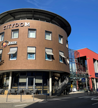 Moderner brauner Rundbau mit Kino und blauem Himmel