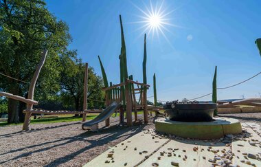 Spielplatz mit Klettergerüst und Rutsche unter blauem Himmel und Sonnenschein. | © Michael Kühneisen