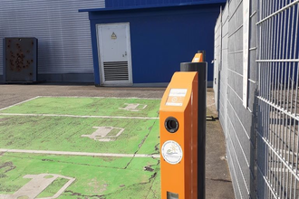E-Ladesäulen zwischen grüner Parkfläche und Zaun
