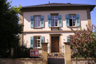 Front des zweistöckigen Dekanatsgebäudes mit blauen Fensterläden und kleinem Vorgarten | © Stadt Sinsheim