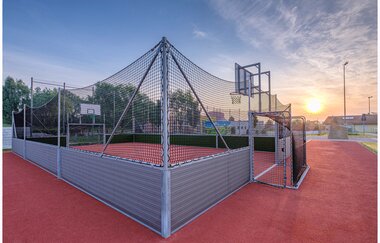 Ein umzäuntes Basketballfeld mit Schutznetz auf einem roten Bodenbelag | © Stadt Sinsheim