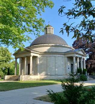 Frasch Mausoleum - Rotunde aus hellem Stein mit dunkelgrauer Kuppel und Laterne, zwei Portikus mit je vier Säulen, umgeben von Rasen und Bäumen | © Petra Natzkowksi