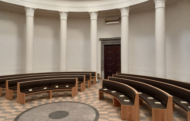 Innenraum des Frasch Mausoleums -vor der Wand weiße Säulen, davor im Halbrund braune Holzbänke mit dunkelbraunen Kissen | © Petra Natzkowski