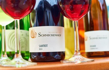 Zwei mit Rotwein gefüllte Gläser und drei Flaschen stehen auf einem Tisch | © Touristikgemeinschaft Hohenlohe e. V.