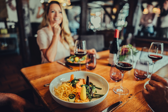 Im Fokus steht ein gedeckter Tisch mit Weingläsern und einem Tellergericht. Der Hintergrund ist unscharf. | © Touristikgemeinschaft HeilbronnerLand