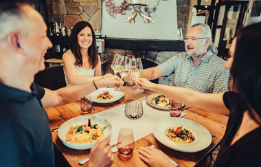 Gastronomieszene als Imagebild. Ein gedeckter Tisch mit vier Personen die mit Wein anstoßen. | © Touristikgemeinschaft HeilbronnerLand