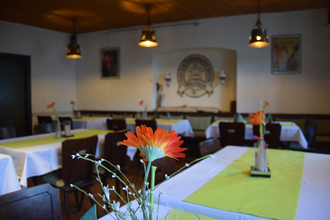 Gedeckte Tische im Gastraum mit grünen Tischdecken und Blumen | © Gasthaus zum Adler Waibstadt