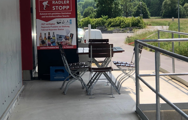 Hier ist ein überdachter Snackautomat abgebildet und einen Tisch mit Stühlen.
