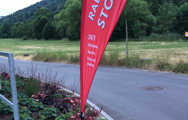 Hier ist einen Beachflag zu sehen, wo drauf Werbung über den Getränke- und Snacksautomaten gemacht wird.