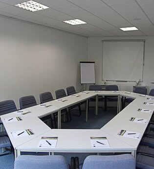 Tische und Stühle in einem Konferenzraum vor einer Leinwand | © Buchenauerhof