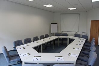 Tische und Stühle in einem Konferenzraum vor einer Leinwand | © Buchenauerhof