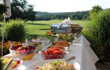 Ein weiß gedeckter Tisch im Freien mit diversen Salaten | © Buchenauerhof