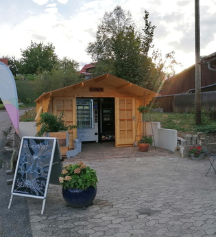 Das Selbstbedinenungshäuschen mit Automat und einem Aufsteller und Beachflag | © Touristikgemeinschaft Hohenlohe e. V. | Familie Fleisch