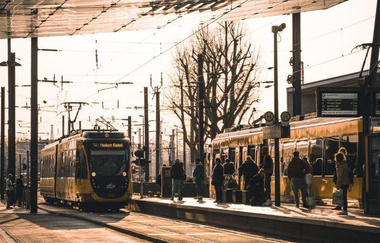Auf dem Bild ist eine einfahrende Stadtbahn zu erkennen, davor sieht man die, in Asphalt eingelassenen, Schienen. Die Haltestelle ist erhöht und rechts neben der Stadtbahn erkennbar. Auf der anderen Seite steigen gerade Gäste in eine weitere Stadtbahn