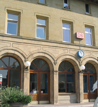 Das Bahnhofsgebäude von außen, hier hängt ein DB-Schild und eine Uhr | © Touristikgemeinschaft Hohenlohe e. V. | Stadt Öhringen
