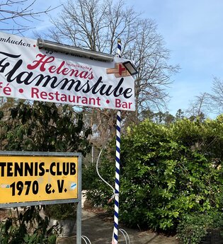 Schild der Flammstube vor den Tennisplätzen